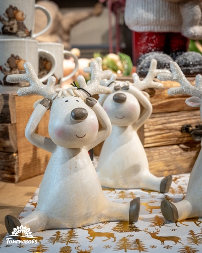 Figurines de rennes souriants avec des bois scintillants sur une nappe de Noël.